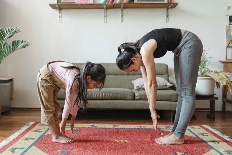 Mother and daughter stretching together in their living room